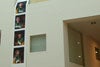 Four photographs displayed on a vertical strip, hanging from an upper floor of the building.