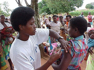 A woman receiving a vaccination at a street clinic as others watch.
