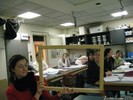 Photo of students stretching a string taught through two empty wooden frames arranged perpendicular to one another on tripods.