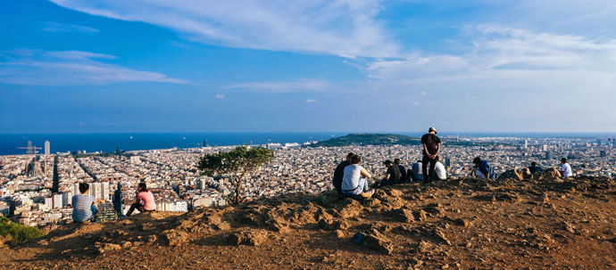Photo of several people on a rocky hilltop overlooking a large city on the ocean coast.