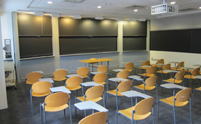 A lecture-style classroom with desks and chalkboards.