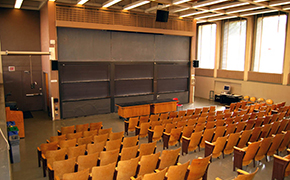 A view toward the front of a classroom from over the rows of seats, showing six sliding chalkboards.