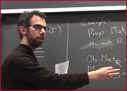 A men standing in front of a blackboard and pointing the blackboard with right hand.