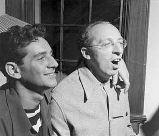 Candid photo: Bernstein's arm around Copland's shoulder; Copland singing.