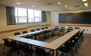 Small black chairs surround tables arranged in the shape of a rectangle.