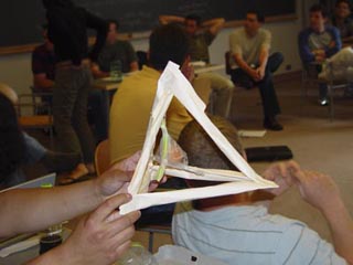 A photograph of a student-constructed egg protection device.  The device consists of a paper pyramid with an egg suspended within. 