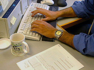 Photo of a man typing on a computer.
