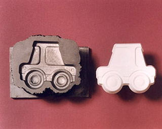 A mold of a toy car and a casting of the car.