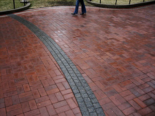 Photo of feet along a brick-paved path.