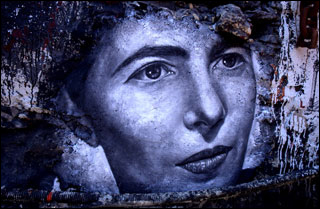 A black and white mural of a woman's face, with  large eyes, a pointed nose, and thin lips, closed in a serious expression.