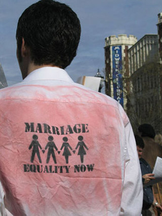 The back of of a man's shirt featuring stencils of two same-sex couples and the message Marriage Equality Now.