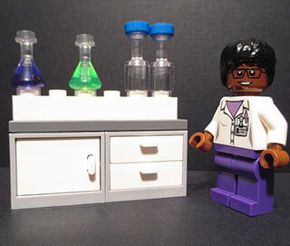 Chemistry equipment and a female African-American scientist are depicted in a Lego® set. 