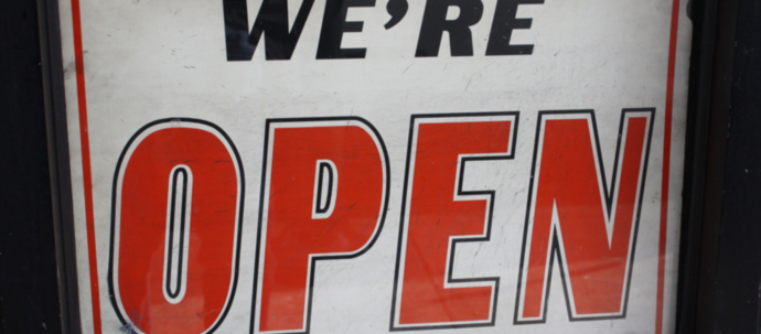 A sign hanging on a glass door that reads 'We're open'.