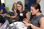 A photo of two girls sitting together, working at a laptop.